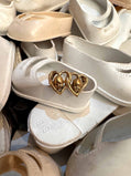 White baby doll shoes as a background for a double heart 14K gold ring with 2 baby doll heads 