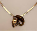 A gold chain necklace featuring a leopard pendant with a gold and black spotted pattern and a small diamond crown, displayed on a neutral beige background.