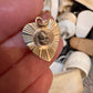 Close-up of hand-sculpted baby face with black diamond eyes soldered onto antique engine-turned heart charm by Karen Yost Anomaly Relic