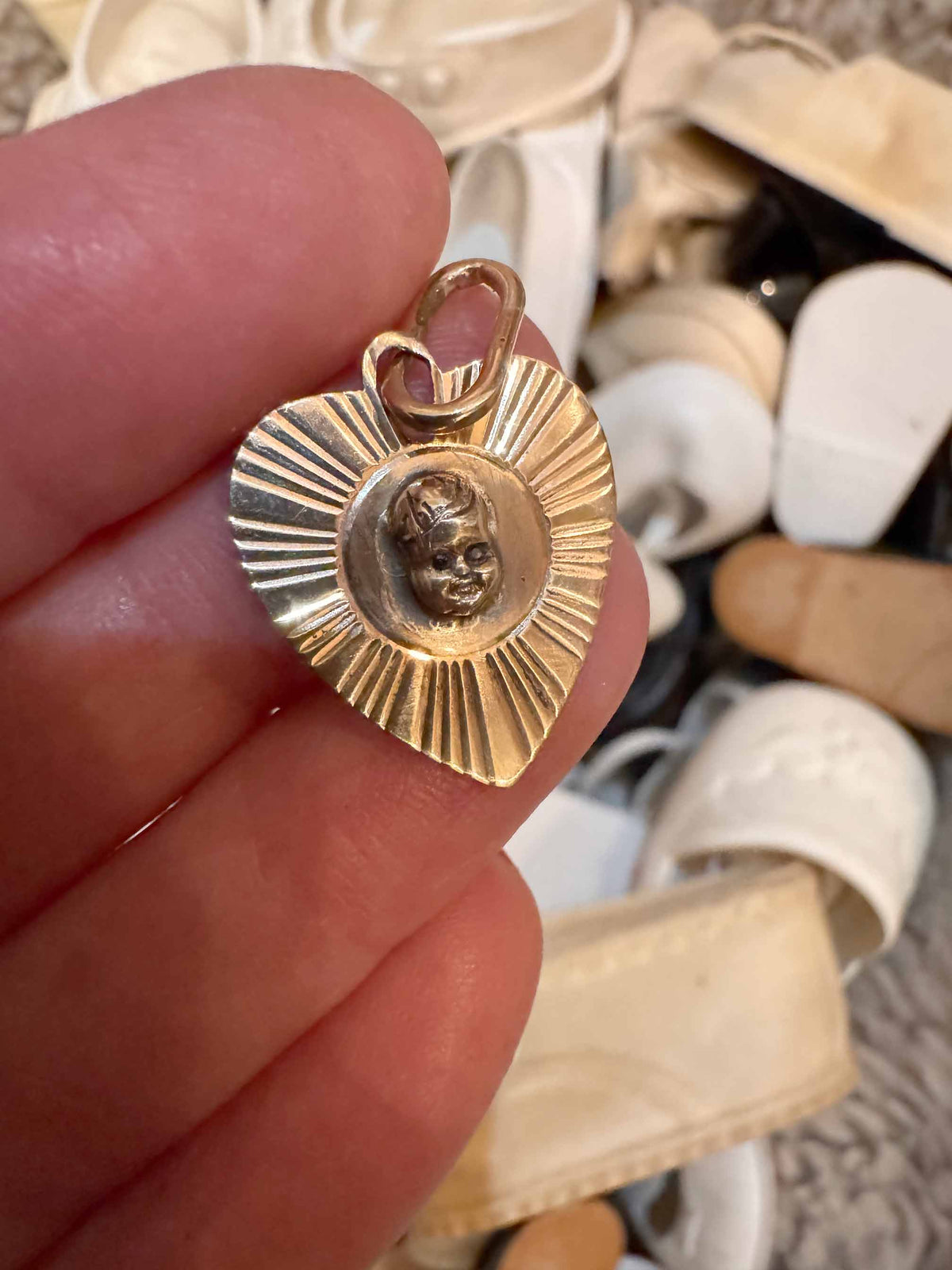 Close-up of hand-sculpted baby face with black diamond eyes soldered onto antique engine-turned heart charm by Karen Yost Anomaly Relic