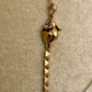 A 14k gold rat pendant necklace featuring a small heart-shaped chain tail with a dangling, articulated heart-link chain