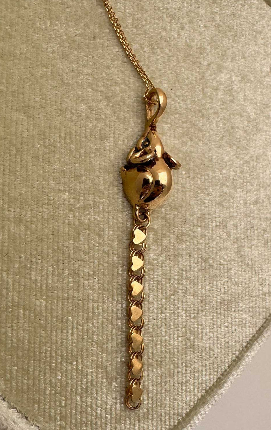 A 14k gold rat pendant necklace featuring a small heart-shaped chain tail with a dangling, articulated heart-link chain