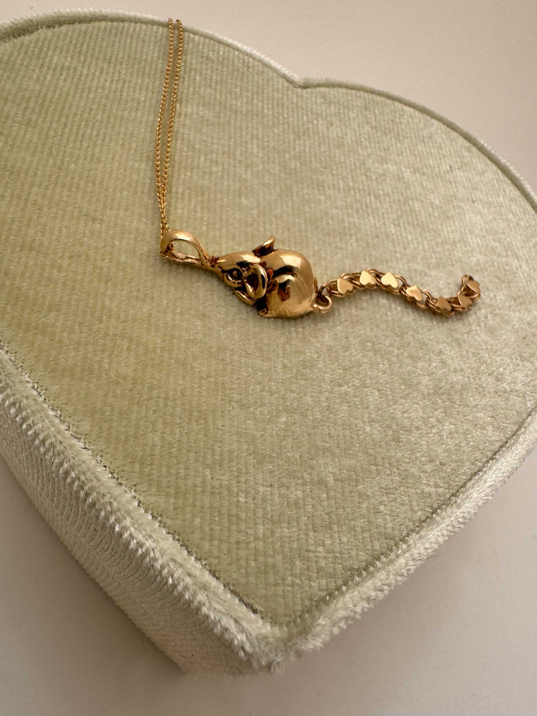 A 14k gold rat pendant necklace featuring a small heart-shaped chain tail with a dangling, articulated heart-link chain