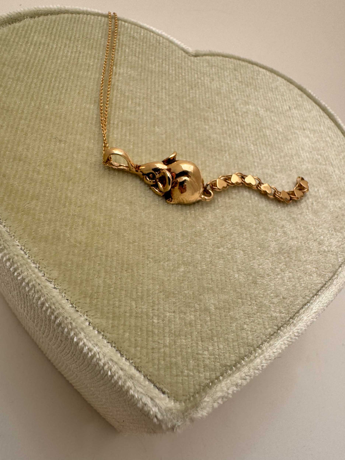 A 14k gold rat pendant necklace featuring a small heart-shaped chain tail with a dangling, articulated heart-link chain