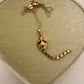 A 14k gold rat pendant necklace featuring a small heart-shaped chain tail with a dangling, articulated heart-link chain