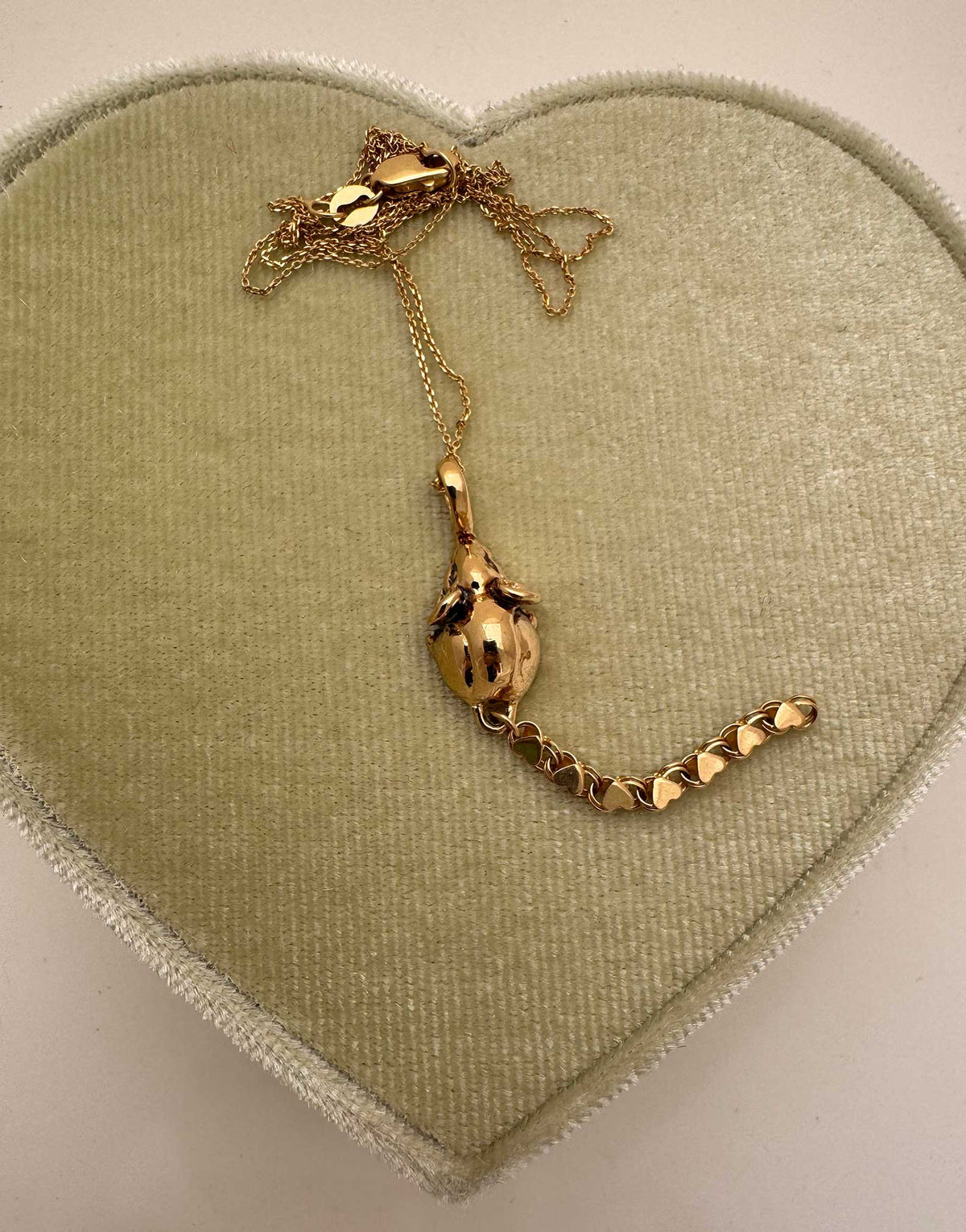 A 14k gold rat pendant necklace featuring a small heart-shaped chain tail with a dangling, articulated heart-link chain